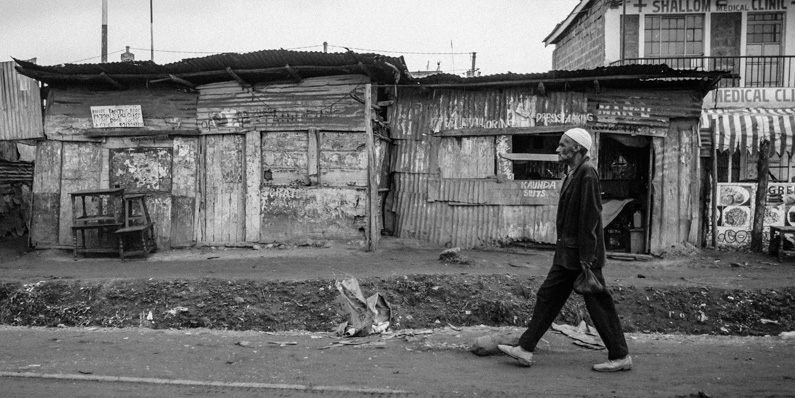 grayscale photo of man walking on road during daytime in Nairobi